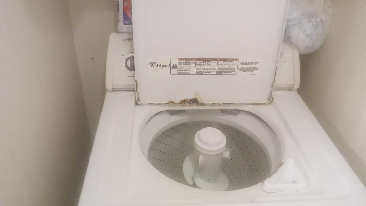 Laveuse à chargement par le haut usagée, couvercle ouvert, traces de rouille sur le rebord